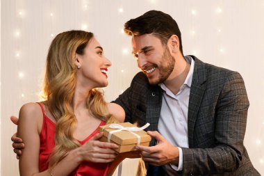 Happy Anniversary. Affectionate Man Giving Gift Box To His Pleased Girlfriend At Romantic Dinner In Restaurant, Empty Space