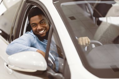 Araba sahibi. Satıcıdan yeni araba sürerken kameraya gülümseyen neşeli afro adam. Seçici Odaklanma