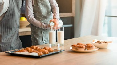 Küçük bir kızın babasıyla mutfakta atıştırması, bardaklara süt dökmesi, taze pişmiş hamur işi tatması, ısırması, ev yemeğinin tadını çıkarması, birlikte evde eğlenmesi, önlük giymesi, bedava yer açması...