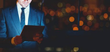 Unrecognizable Businessman Using Tablet Computer Working Standing In Modern Office At Night. Business Lifestyle. Cropped, Copy Space, Panorama