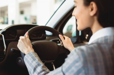 Yalnız araba kullanmak. Tanımlanamayan bir kadın arabayı test ediyor, omzunun üstünden dikiz aynası görüyor, direksiyona odaklanıyor.