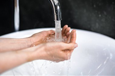 Hijyen el yıkama. Evdeki Banyo 'da tanınmayan kadın ellerini yıkıyor. Panorama, Kırpılmış, Kapalı