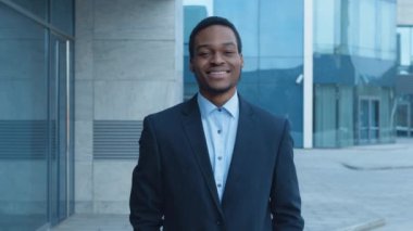 Çağdaş bir ofis binasının önünde resmi giysiler içinde gülümseyen genç bir Afrikalı Amerikalı profesyonel bir ortama güveni tam..