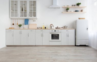 Gündüz hafif mutfak, basitçe, minimalist İskandinav iç mekanı. Beyaz mobilyalar, küçük buzdolabı, çatal bıçaklı ocak, sökücü kapağı, saksıda bitkiler, sabahları perdeler.