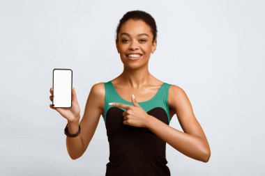 Spor Uygulamaları. Afrikalı Amerikalı Kız, Smartphone Gösteren Boş Ekran Parmak Gösteren Sarı Stüdyo Arkaplanı. Model