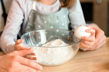 Küçük bir kızın bovling oynamak için yumurta kırması, babama hamur işlerinde yardım etmesi, evde pişirmekten hoşlanması, kesilmiş görüntüler.