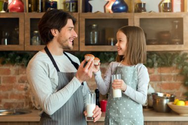 Babamla atıştırma zamanı. Mutlu küçük kız ve babası kek yiyor ve mutfakta süt içiyor, bedava yer var.