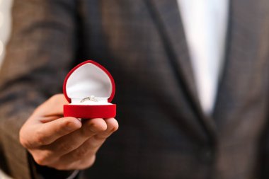 Teklif Konsepti. Elinde elmas yüzük ve gül buketi olan tanınmamış bir adam evlenme teklif ediyor.