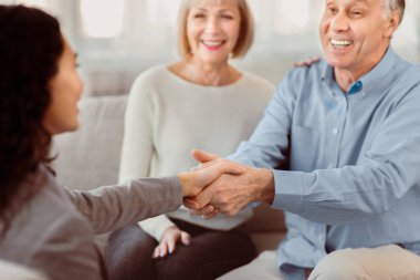 Gratitude. Close up of handshake of happy mature man and female doctor greeting each other at couple therapy session