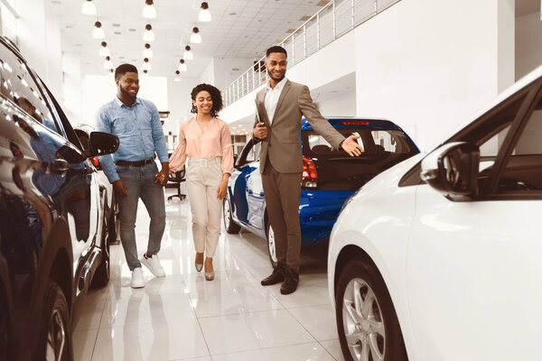 Продавец автомобилей показывает Роскошный автомобиль Консалтинг пара выбирая автомобиль в дилерском магазине. Покупка концепции транспортного средства