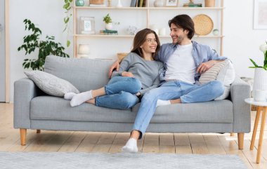 Genç çift evdeki kanepede birbirine sarılıyor, birbirlerine bakıyorlar, enpty space