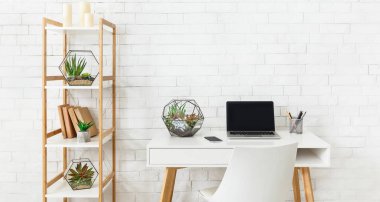 Dizüstü bilgisayar ile ev çalışma yeri, ve beyaz tuğla duvar arka planda rafta ev bitkileri. Minimalist modern iç mekan konsepti, kopyalama alanı