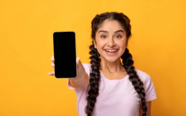 Moda Cep Telefonu. Elinde siyah bir ekranla cep telefonu tutan neşeli, genç Hintli kadın portresi, cihazı gösteriyor. Modelleme, seçici odak, bulanıklık için boş alanı olan Gadget