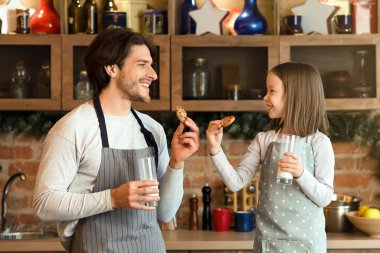Baba ve küçük kız mutfakta yemek yiyorlar, birlikte süt içiyorlar, evde vakit geçiriyorlar.