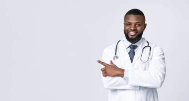 Dikkat edin, reklam için yer var. Kolları çaprazlanmış dost canlısı siyah doktor beyaz arka plan, panorama üzerindeki boşluğu işaret ediyor.