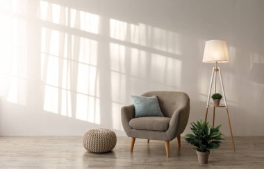Yastıklı rahat retro koltuk, parlak lamba ve saksıdaki bitki, oturma odasındaki gri duvardaki döşeme. İskandinav tarzı rahat bir iç mekan, mobilyalı çağdaş tasarım.