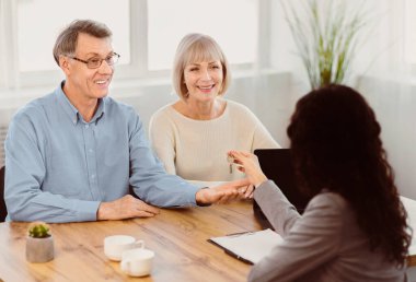 New Owners. Happy senior couple getting keys from female real estate agent, copyspace