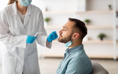 Kapsamlı tanı prosedürü. Doktor, evde steril bez çubuğu kullanan beyaz bir adam için nazal PCR testi yapıyor. Milenyum adamı koronavirüs analizinden geçiyor, sağlık kontrolü yapıyor.