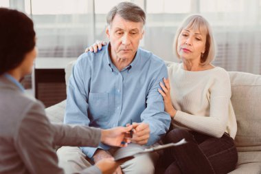 Sign Here Please. Unrecognizable female real estate agent offering home ownership and life insurance to mature couple