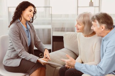 Tasarruf Planı. Mortgage kredilerini tartışan mutlu olgun çifte yeni yatırımlar gösteren bir finans danışmanı.