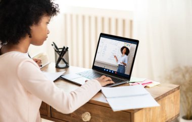 E-Öğrenme Konsepti. Laptop 'taki Afrikalı Liseli Kız, evde öğretmeniyle çevrimiçi ders alıyor. Seçici Odaklanma