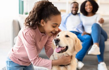 Gülümseyen Afrikalı Amerikalı kızın portresi kulağına bir şeyler fısıldıyor, sırlarını anlatıyor ve mutlu bir köpek yetiştiriyor, en iyi arkadaşıyla oturma odasında vakit geçiriyor, seçici bir şekilde odaklanıyor.