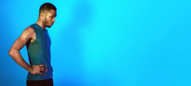 Spor Giyim 'de siyahi bir adam nefes egzersizi yapıyor idmana hazırlanıyor mavi stüdyonun arka planında duruyor. Boş Alan, Neon Işıkları