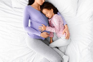 Genç bir bayanın evde küçük kızıyla kestireceğinin huzurlu bir görüntüsü.