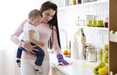 Doğum izninde ev işleri. Evde mutfak temizliği erkek bebek ile genç anne, boş alan