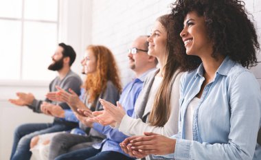 Başarıyı takdir ediyorum. Çeşitli insanlardan oluşan bir grup toplantıda el çırpıyor.