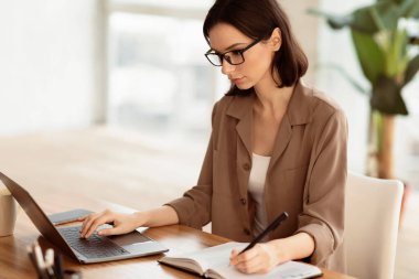 Kadın Asistanı. Modern ofiste dizüstü bilgisayar kullanan genç ve güzel bir resepsiyonist.