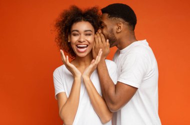 Afrikalı-Amerikalı kız gülmüyorum, dinleme nasıl sevgilisi fısıldayan gizli ya da dedikodu, turuncu studio arka plan