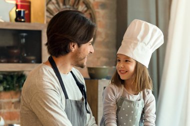 Şefin şapkasındaki neşeli küçük kız ve babası mutfakta pasta hazırlıyor, öksürük örüyor ve evde eğleniyor, uzay kopyaları yapıyor.
