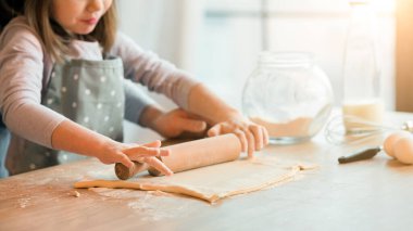 Baba ve kızı kurabiye yapmak için mutfakta hamuru birlikte yuvarlıyor, ahşap oklamalı iğne kullanıyor, evde yemek pişiriyor, ev yapımı hamur işlerinin keyfini çıkarıyor, pizza pişiriyor, pişirmeyi seviyor, boş alanlı kırpılmış imgeleri seviyor.