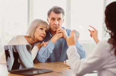 Reçete konsepti. Kadın doktor elinde ilaç kavanozuyla ofisteki üzgün yaşlı çifte talimat veriyor.