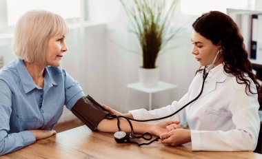 Kardiyoloji. Meksikalı doktor yaşlı kadının kan basıncını ölçüyor, hastayı kontrol ediyor, boş yer, panorama