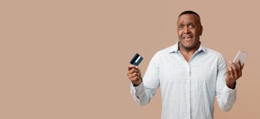 Çevrimiçi işlem sorunu. Kafası karışmış Orta Afrikalı Amerikalı adam mobil bankacılık ve kredi kartı kullanıyor.