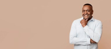 Olgun, turuncu arka planda çenesine dokunan Afrikalı bir adam.