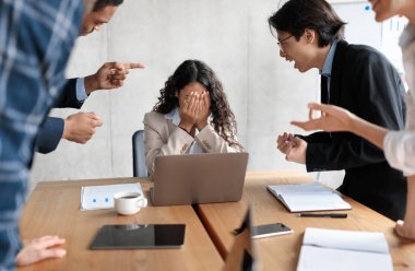 Workplace Conflict And Bullying. Aggressive Coworkers Yelling At Victimized Businesswoman Sitting At Desk In Modern Office. Corporate Communication Problem, Quarrels And Bad Attitude At Work