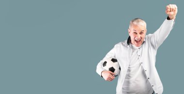 Gol 'u kutluyoruz. Futbol topuyla poz veren amigoluk yapan, kazanan jest yapan, mavi stüdyo duvarı