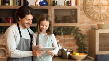 Babası ve küçük kızı, dijital tablet kullanıyorlardı. Yemek hazırlamak için, mutfakta birlikte yemek yapıyorlardı.