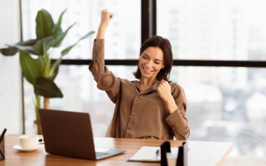 Yes. Portrait of excited beautiful young woman celebrating success using laptop, working in living room at home