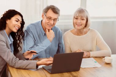 Yolculuk için hazırlanıyorum. Meksikalı seyahat acentesi yaşlı müşterilerle çalışıyor ve onlara dizüstü bilgisayar kullanarak ofiste turlar teklif ediyor.