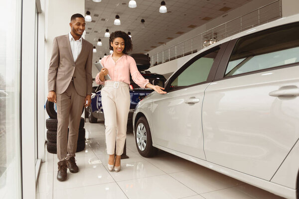 Продажа автомобилей. Африканский бизнесмен выбирает роскошный автомобиль у автопродавца в автосалоне. Пустое место для текста
