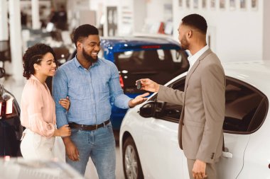 Oto satın almak. Satıcı, test sürüşü için araba anahtarlarını alıcılara veriyor. Lüks satış merkezinde duruyor..