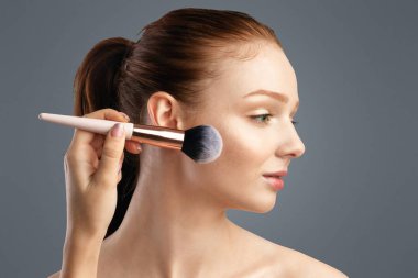 Kızıl Saçlı Milenyum Kızı Kozmetik Fırça ile Makyaj Yapıyor Beyaz Stüdyo Arkaplanı 'na farklı pozlar veriyor. Boş Alanlı Makyaj Reklamları