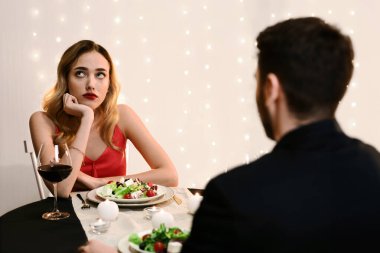 Unsuccessful Date. Young woman feeling bored at dinner in restaurant, looking away with disappointed face expression, selective focus