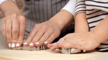 Bir ebeveyn ve çocuk hamuru şekillendirmek için kurabiye keskisi kullanıyor, sıcak bir mutfakta kaliteli zaman geçiriyorlar..