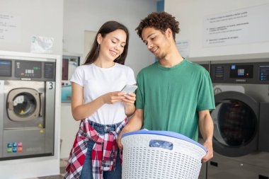 Genç bir çift çamaşırhanede birbirlerine eşlik etmekten zevk alır. Biri telefonlarını kontrol ederken diğeri de çamaşır sepetini tutar. Hem güler hem de angarya işleri sırasında rahatlar..