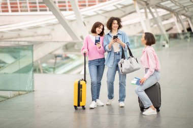 Three friends gather in an airport terminal, preparing for their journey. They are checking their devices, holding passports, and discussing travel details while surrounded by a modern, airy space. clipart